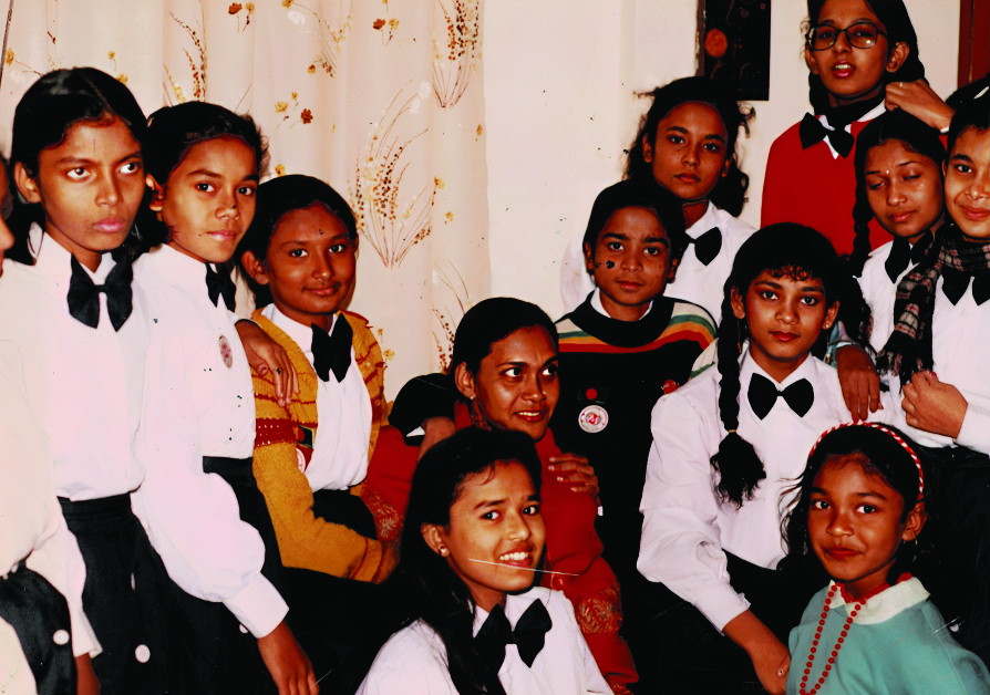 A close group of children in white shirts and black bow ties, turned towards the camera