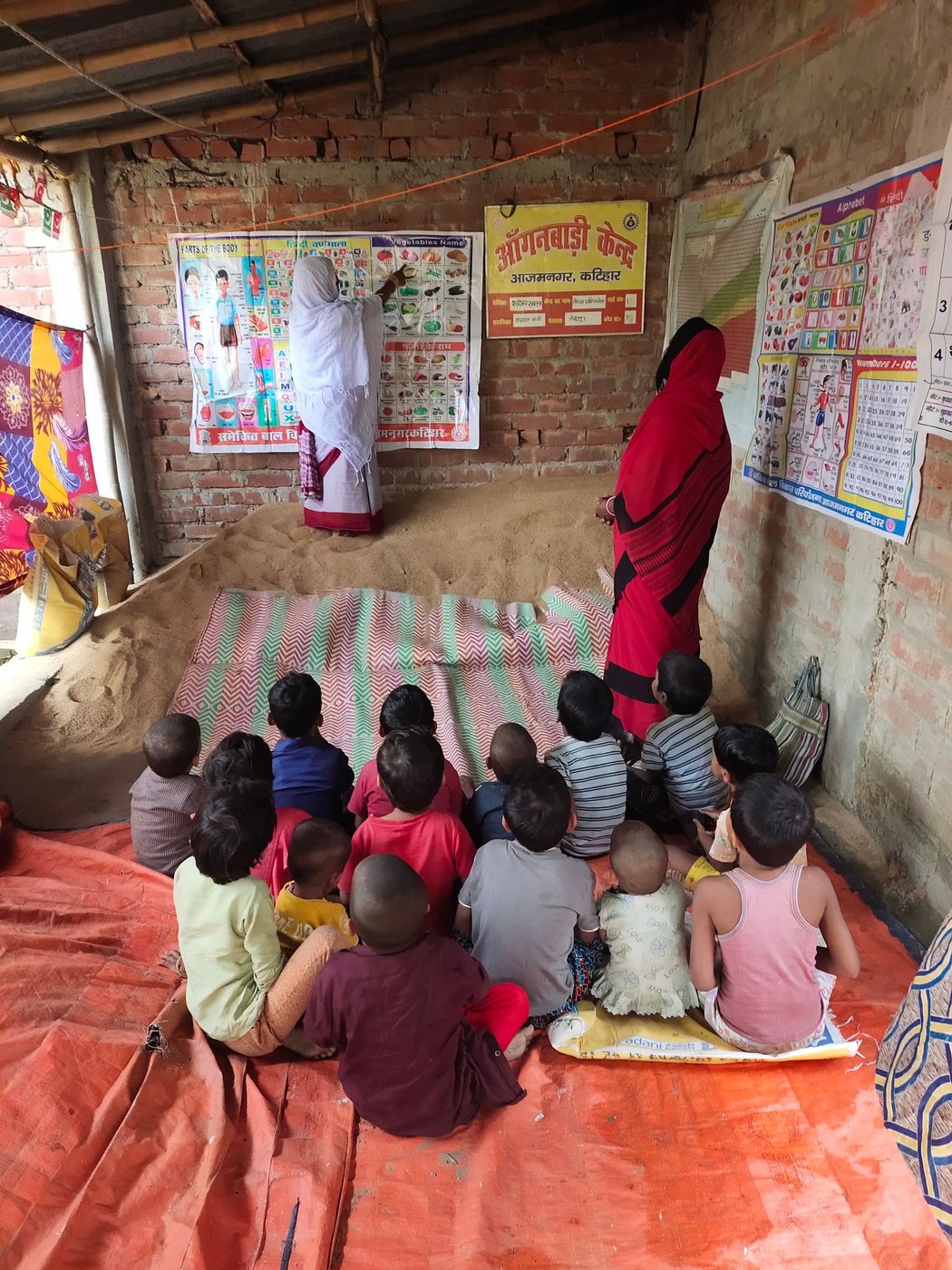 A classroom seen from the back, children at desks facing the blackboard. A rural classroom seen from the back, India.